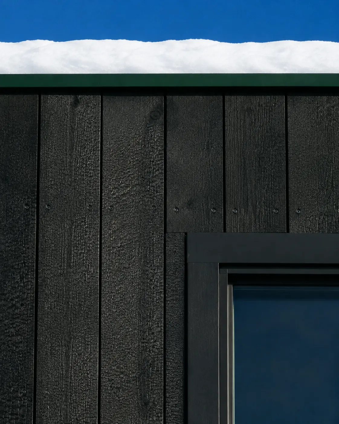 Dark charred-timber cladding and precise black window frame at Pine House