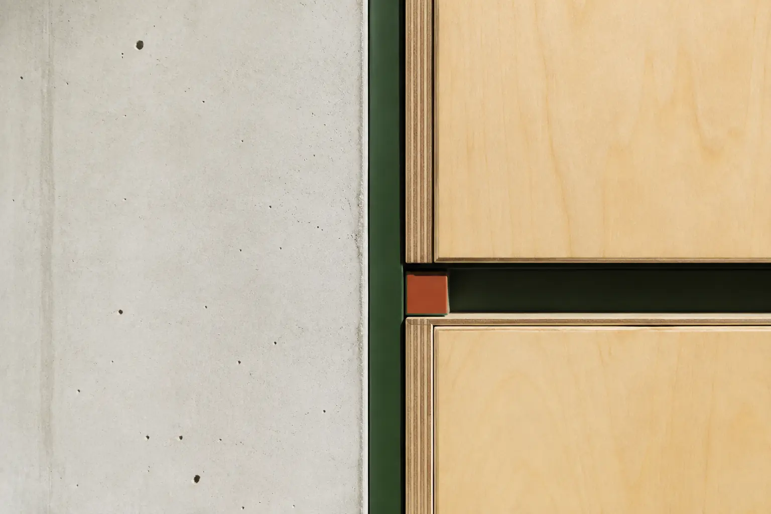 Architectural concrete meeting pale birch plywood and green metal trim