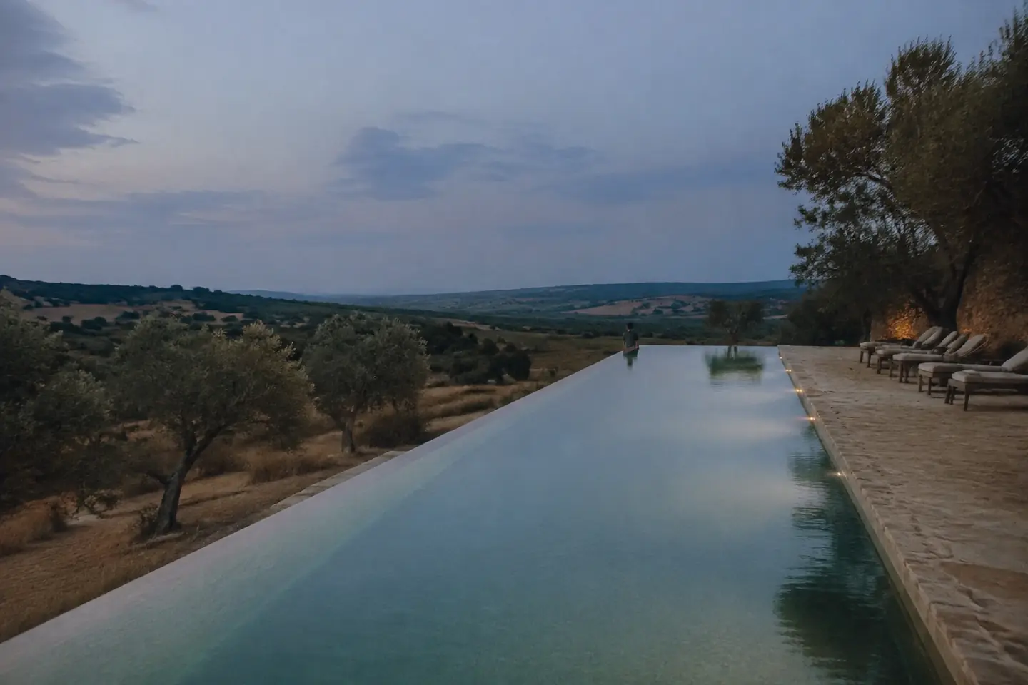 Infinity pool overlooking a quiet Mediterranean valley at blue hour