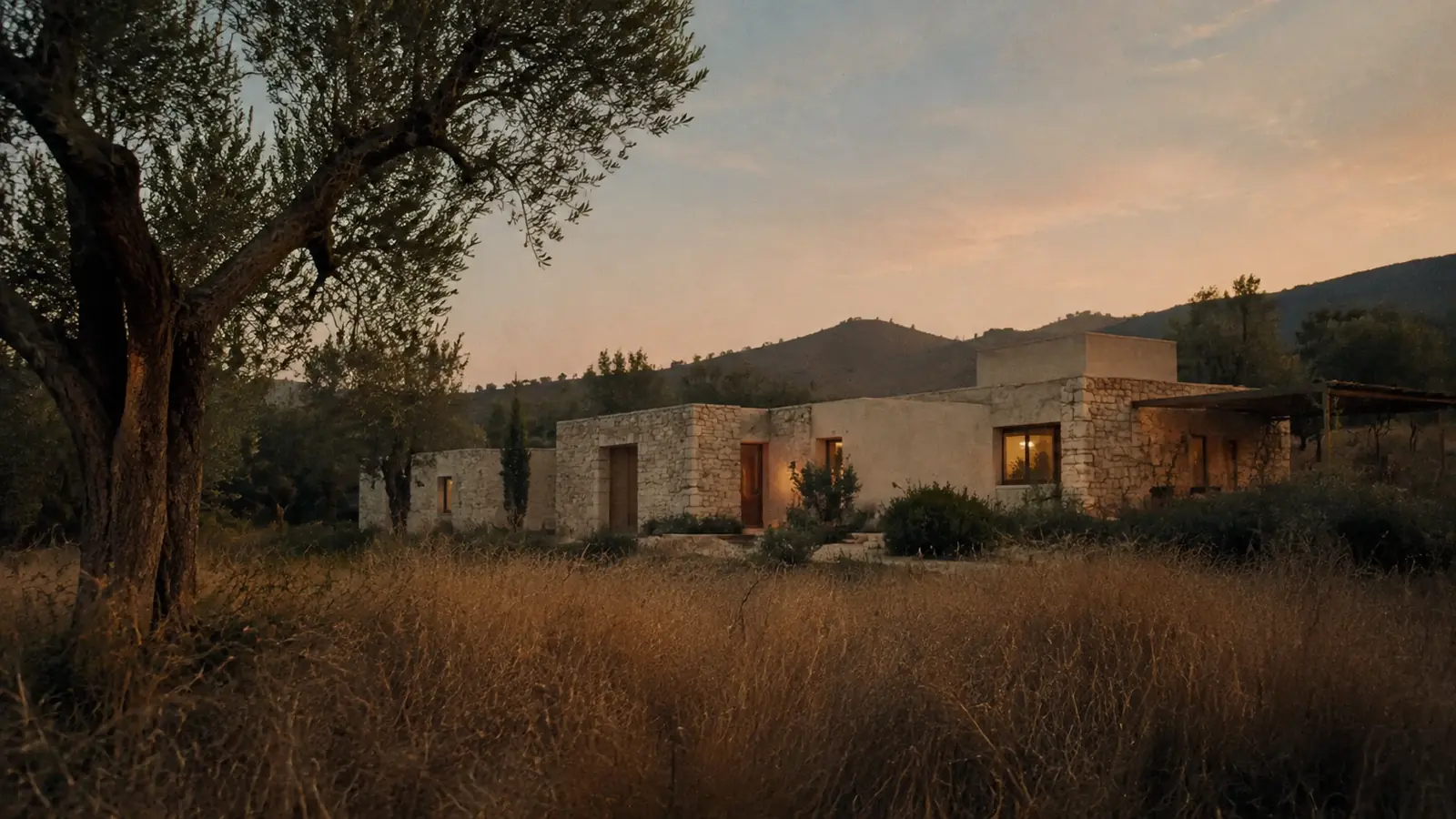 Aster House glowing softly in the Mediterranean landscape at sunset