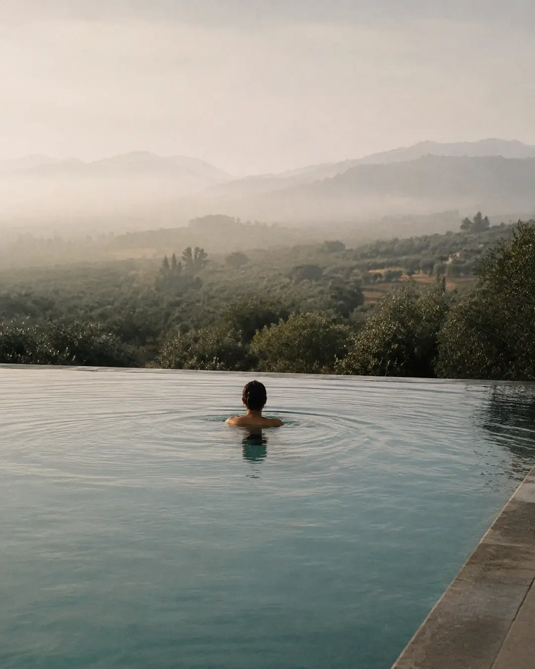 A guest swimming in the infinity pool above the valley